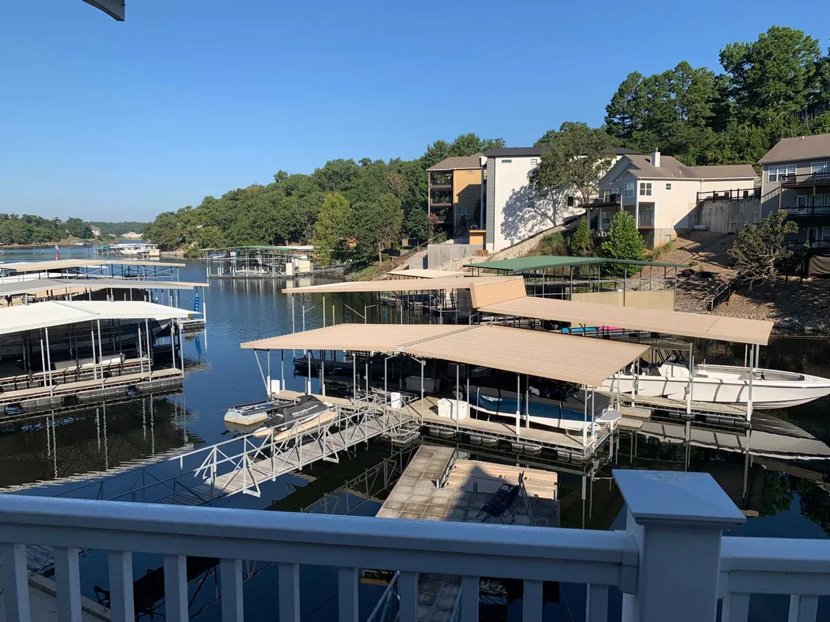 A scenic lakeside view featuring a marina with multiple boats docked, expansive water, and lush greenery framing the shoreline. The docks are bustling with boating activity and offer peaceful spots for fishing or relaxing by the water.