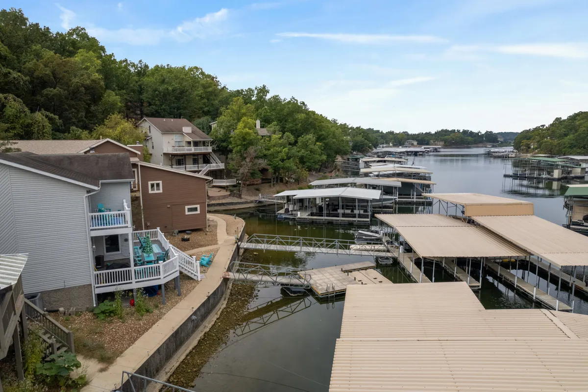 A tranquil view across the lake, showcasing houses along the shore and marinas in the distance. The gently sloped shoreline provides ample open space for relaxing or playing, with opportunities for boating and paddleboarding visible. The scene feels peaceful and inviting, perfect for leisurely days outdoors.